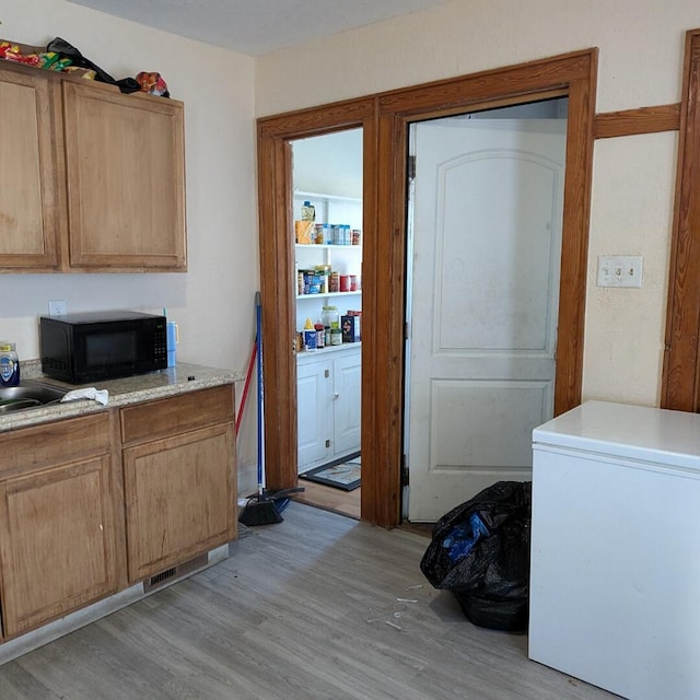 kitchen with fridge and light wood-type flooring