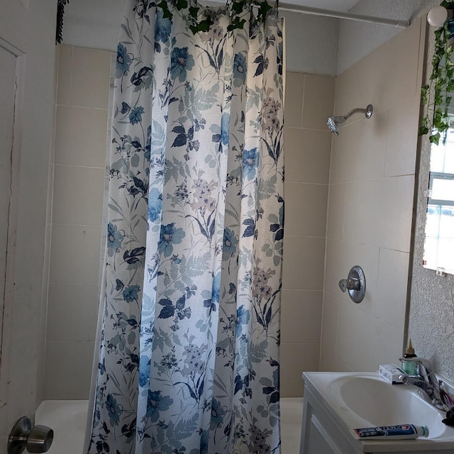 bathroom with a tile shower and vanity