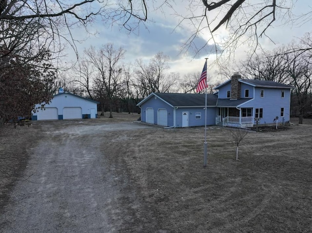 view of front of home featuring covered porch, a garage, and an outdoor structure