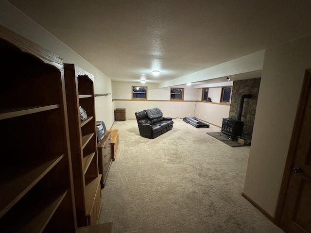 basement featuring light carpet, a wood stove, and a textured ceiling