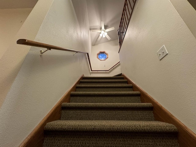 stairs featuring ceiling fan