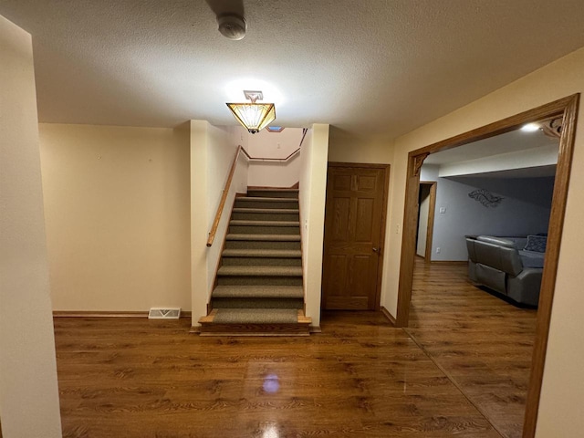 stairs with wood-type flooring and a textured ceiling