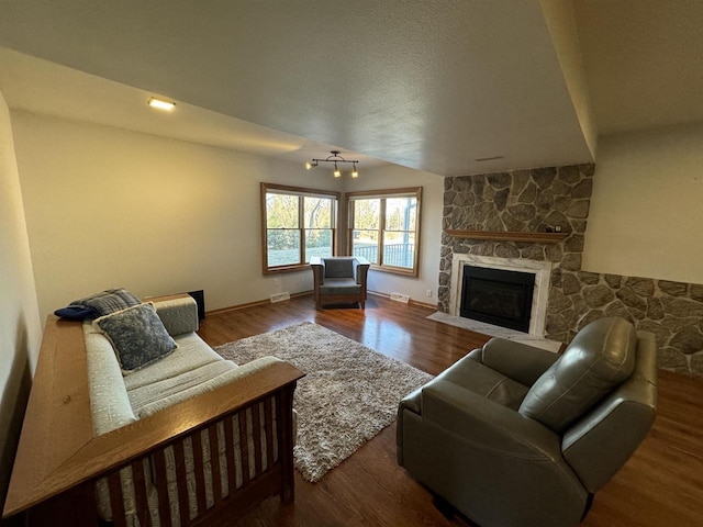 living room with hardwood / wood-style flooring and a stone fireplace