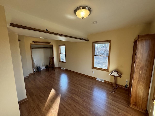 empty room with a wealth of natural light and dark hardwood / wood-style floors