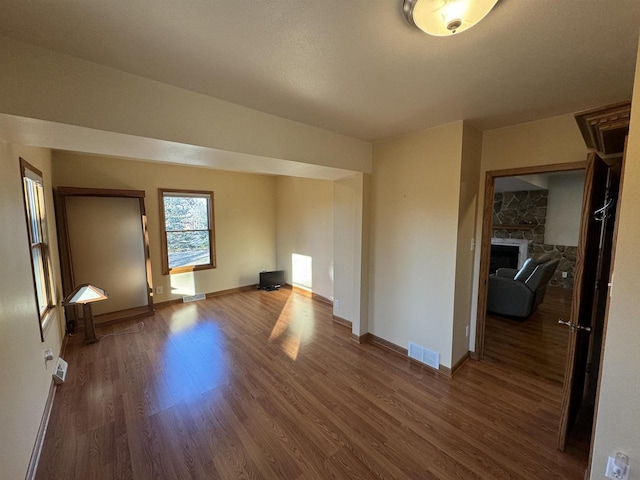 unfurnished living room featuring dark wood-type flooring and a fireplace