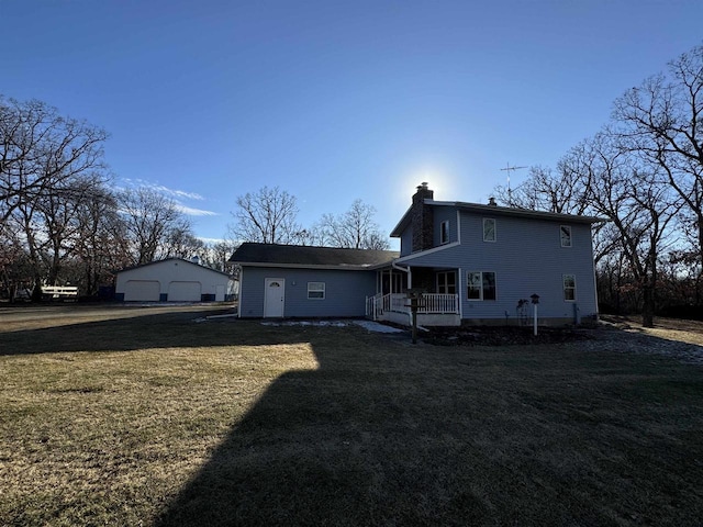 back of house with a garage, a lawn, an outdoor structure, and a porch