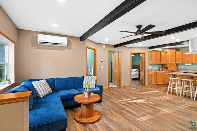 living room featuring ceiling fan, a wall mounted AC, hardwood / wood-style flooring, and beamed ceiling