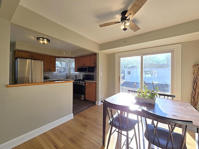 kitchen featuring ceiling fan, backsplash, sink, light hardwood / wood-style flooring, and appliances with stainless steel finishes