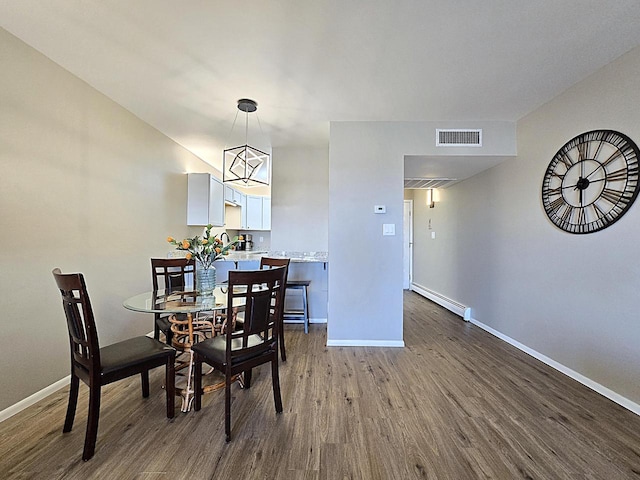 dining room featuring baseboard heating, a chandelier, and hardwood / wood-style floors