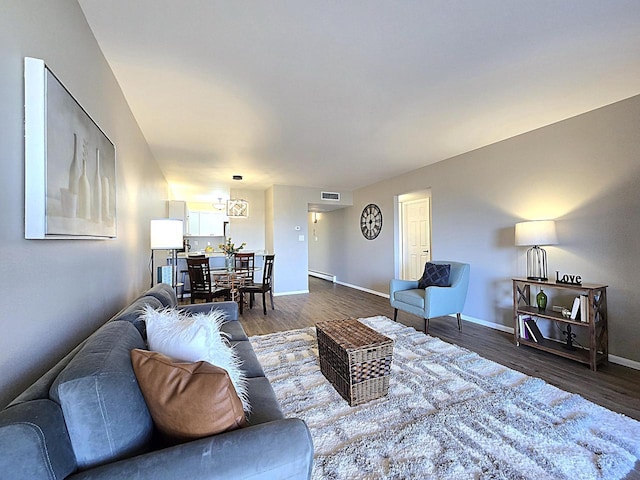 living room with dark wood-type flooring, baseboard heating, and a chandelier