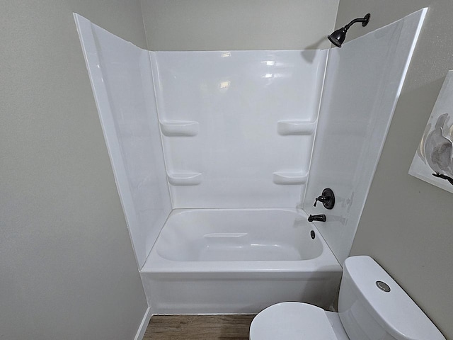 bathroom with washtub / shower combination, toilet, and wood-type flooring