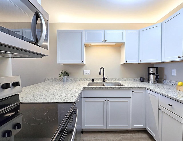 kitchen featuring hardwood / wood-style flooring, appliances with stainless steel finishes, white cabinetry, and sink