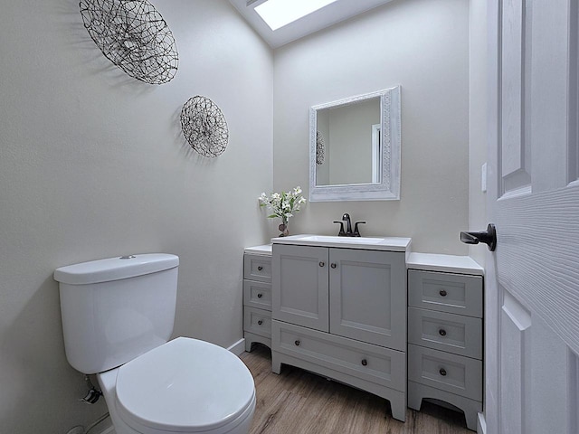 bathroom featuring toilet, vanity, a skylight, and wood-type flooring