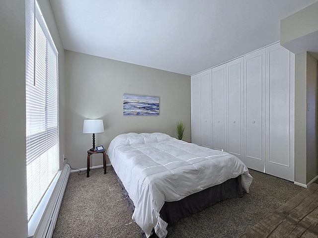 bedroom with a baseboard heating unit, a closet, and dark carpet