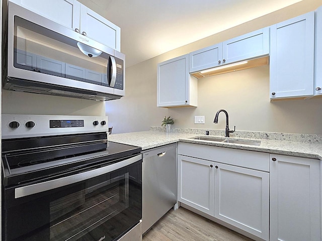 kitchen featuring light wood-type flooring, sink, stainless steel appliances, and white cabinetry