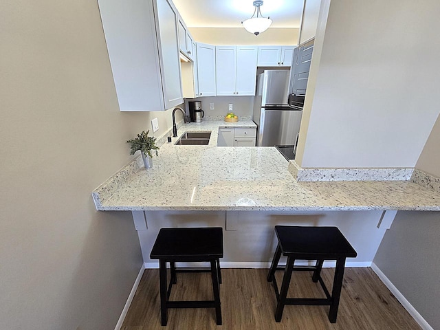 kitchen with a kitchen breakfast bar, white cabinets, sink, and kitchen peninsula