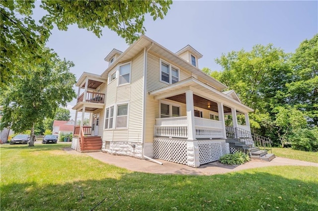 rear view of property featuring covered porch, a yard, and a balcony