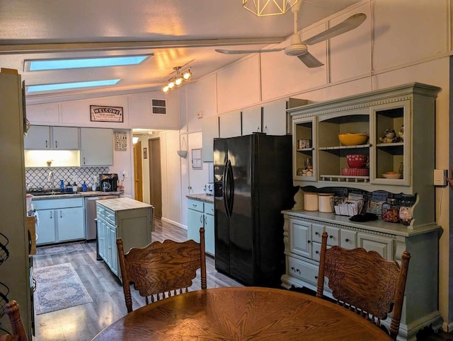 kitchen featuring tasteful backsplash, vaulted ceiling, a kitchen island, butcher block countertops, and black fridge with ice dispenser