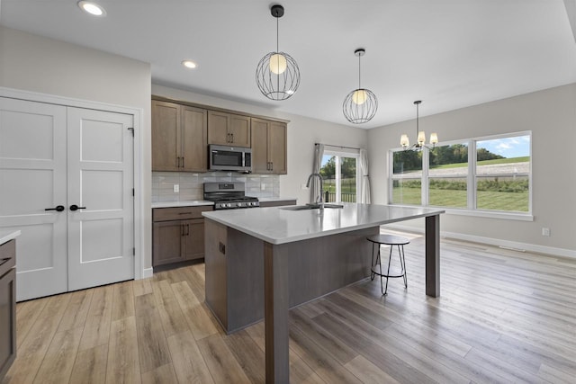 kitchen featuring appliances with stainless steel finishes, tasteful backsplash, an inviting chandelier, sink, and hanging light fixtures