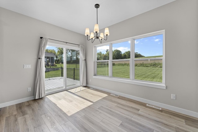 empty room with an inviting chandelier and light hardwood / wood-style floors