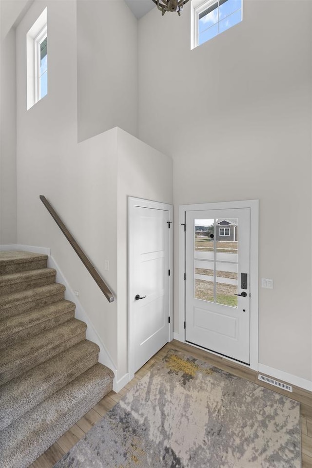 foyer entrance with light hardwood / wood-style floors, a high ceiling, plenty of natural light, and a notable chandelier