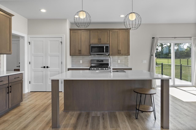 kitchen with appliances with stainless steel finishes, sink, backsplash, and decorative light fixtures