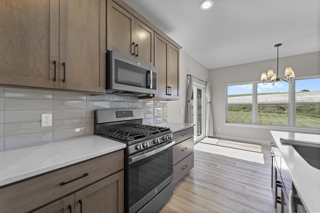 kitchen with backsplash, hanging light fixtures, stainless steel appliances, and an inviting chandelier