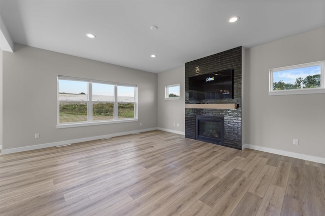 unfurnished living room featuring a fireplace and light hardwood / wood-style floors