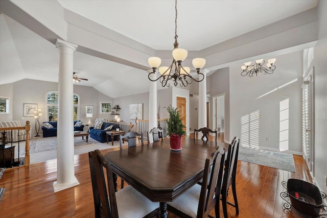 dining area featuring ceiling fan with notable chandelier, hardwood / wood-style floors, decorative columns, and vaulted ceiling