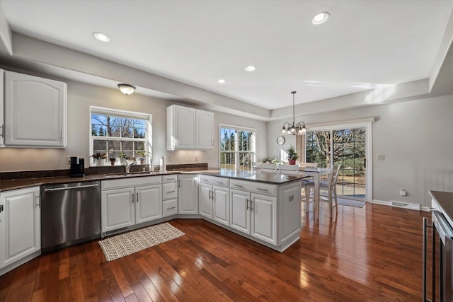 kitchen featuring white cabinets, dishwasher, dark wood-type flooring, hanging light fixtures, and kitchen peninsula