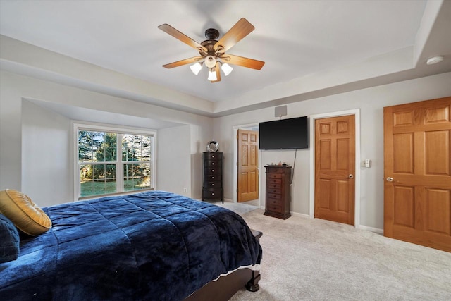 carpeted bedroom with ceiling fan, a closet, and a raised ceiling