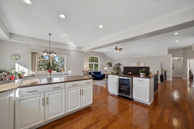 kitchen featuring ceiling fan with notable chandelier, beverage cooler, decorative light fixtures, white cabinetry, and dark hardwood / wood-style flooring