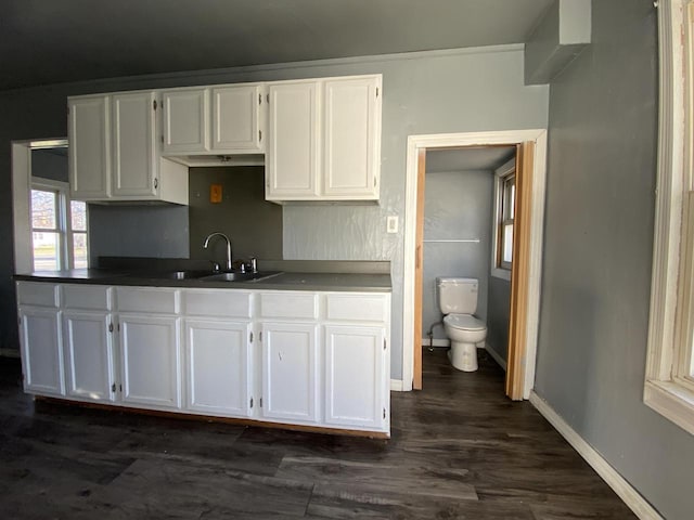 kitchen featuring dark wood-type flooring, sink, and white cabinetry