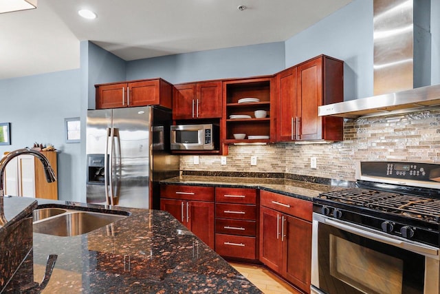 kitchen with wall chimney range hood, dark stone countertops, sink, backsplash, and stainless steel appliances