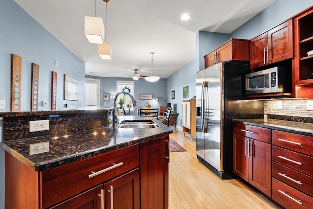 kitchen with tasteful backsplash, dark stone counters, sink, decorative light fixtures, and stainless steel appliances