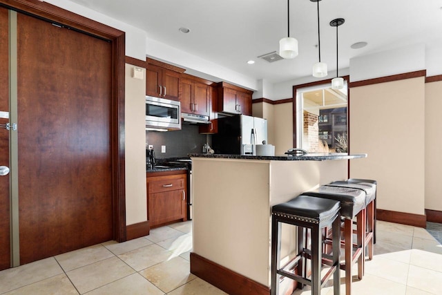 kitchen with light tile patterned flooring, a kitchen breakfast bar, stainless steel appliances, and tasteful backsplash