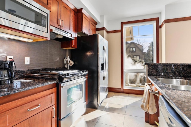 kitchen with light tile patterned flooring, tasteful backsplash, dark stone countertops, and stainless steel appliances