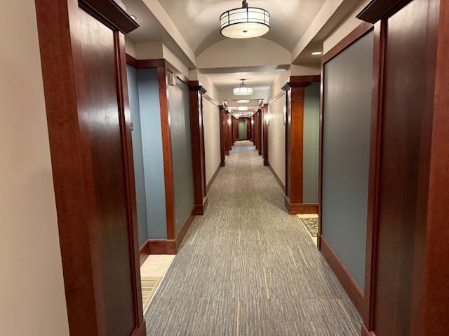 corridor with vaulted ceiling and light carpet