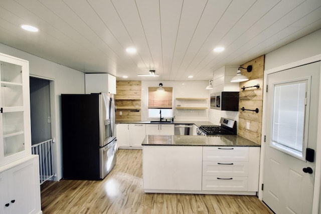 kitchen with light hardwood / wood-style flooring, dark stone countertops, stainless steel appliances, and white cabinetry