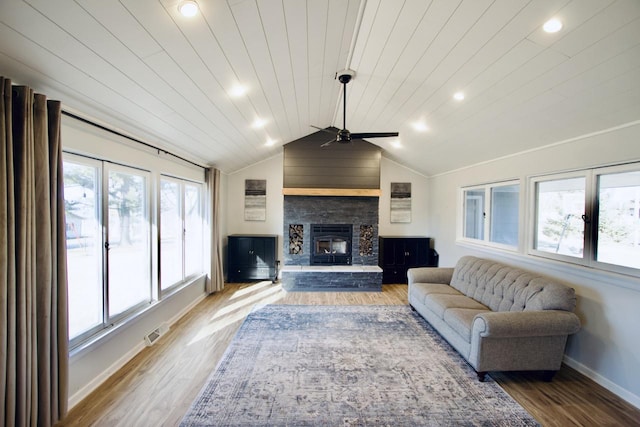 living room featuring wood-type flooring, a stone fireplace, vaulted ceiling, ceiling fan, and wooden ceiling