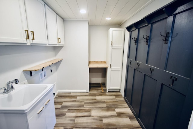 clothes washing area with light hardwood / wood-style floors, sink, hookup for a washing machine, electric dryer hookup, and cabinets