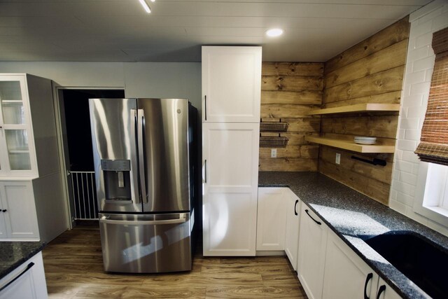 kitchen featuring stainless steel refrigerator with ice dispenser, dark hardwood / wood-style flooring, white cabinets, and dark stone counters