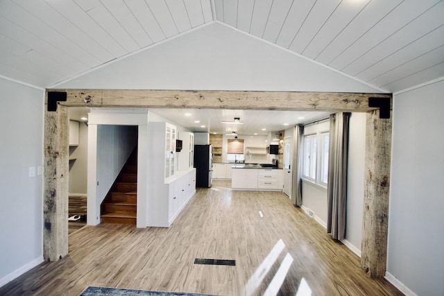 unfurnished living room featuring lofted ceiling, wooden ceiling, ornamental molding, and light hardwood / wood-style floors