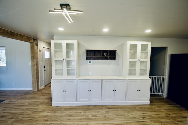 bar with light hardwood / wood-style floors and white cabinetry