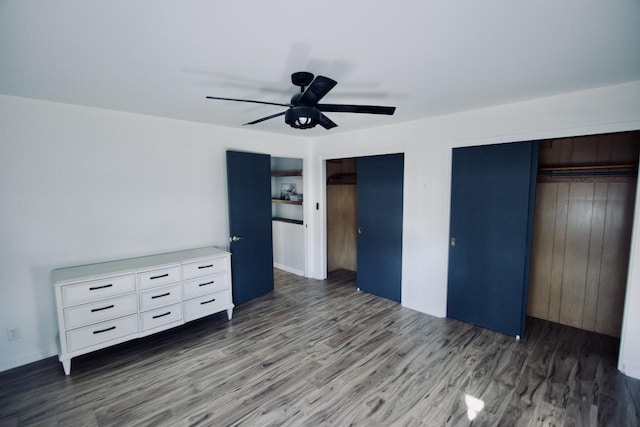 unfurnished bedroom featuring ceiling fan, dark hardwood / wood-style flooring, and two closets