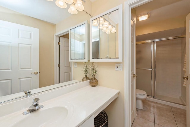 bathroom with toilet, tile patterned flooring, a shower with shower door, and sink