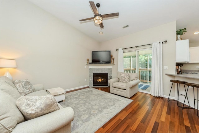 living room with ceiling fan, dark wood-type flooring, vaulted ceiling, and a fireplace