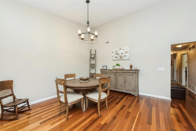 dining area featuring a high ceiling, dark hardwood / wood-style floors, and a notable chandelier