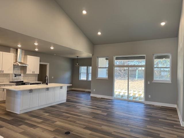 kitchen featuring white cabinetry, wall chimney range hood, dark hardwood / wood-style floors, and an island with sink