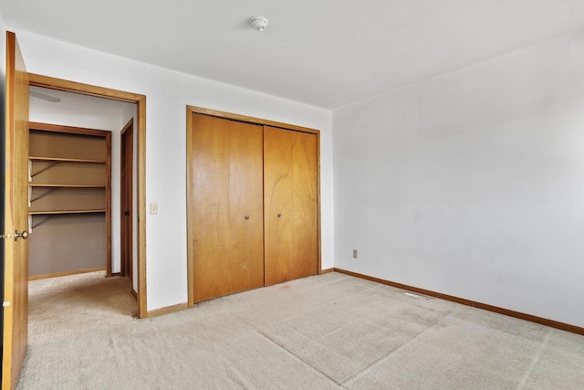 unfurnished bedroom with a closet, baseboards, and light colored carpet